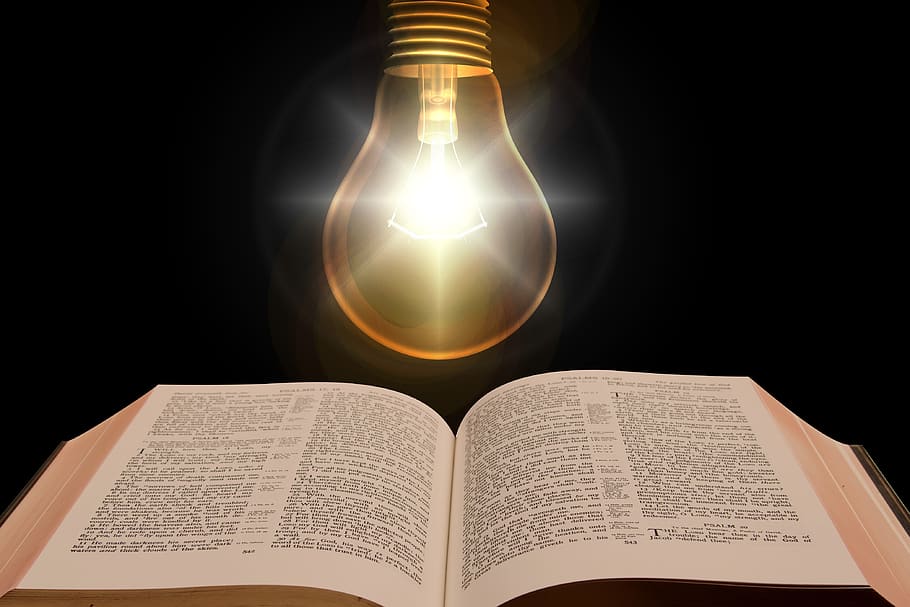 An open Bible lit by a glowing light bulb